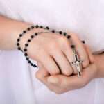 Young woman's hands with a dainty cross necklace