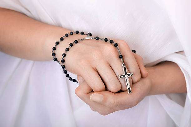 Young woman's hands with a dainty cross necklace